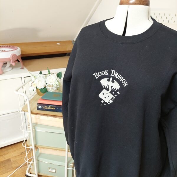 Cozy sweatshirts featuring the phrase "Book Dragon" prominently displayed on the chest. Perfect for book lovers!