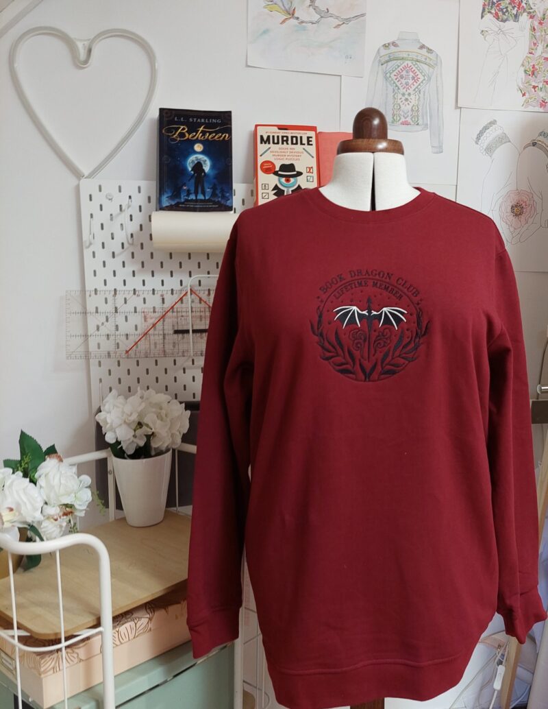 Cozy sweatshirts featuring the phrase "Book Dragon Club Lifetime member " prominently displayed on the chest. Perfect for book lovers!