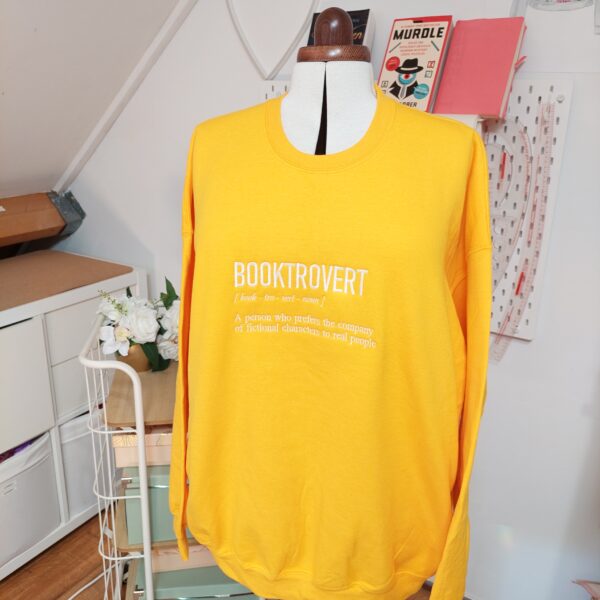 A cozy sweatshirt featuring the phrase "Booktrovert" prominently displayed on the chest. Perfect for book lovers!