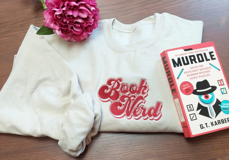 A cozy sweatshirt featuring the phrase "Book Nerd" prominently displayed on the chest. Perfect for book lovers!