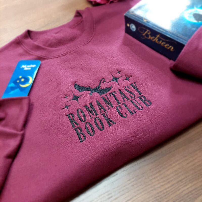 A cozy sweatshirt featuring the phrase "Romantasy Book club" prominently displayed on the chest. Perfect for book lovers!