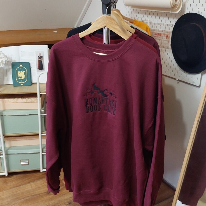 A cozy sweatshirt featuring the phrase "Romantasy Book club" prominently displayed on the chest. Perfect for book lovers!