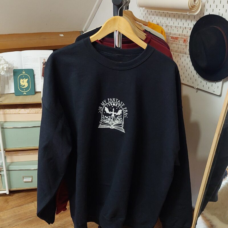 A cozy sweatshirt featuring the phrase "In my Fantasy Era" prominently displayed on the chest. Perfect for book lovers!