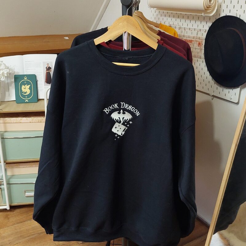 Cozy sweatshirts featuring the phrase "Book Dragon" prominently displayed on the chest. Perfect for book lovers!